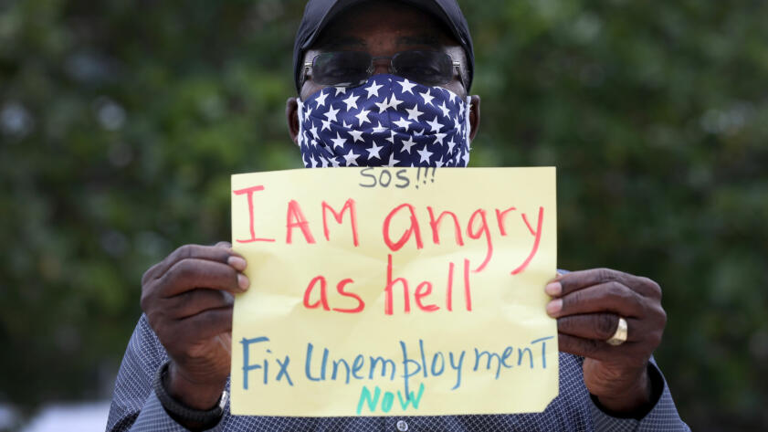 A Floridan protester holds up a sign that reads "I am angry as hell. fix unemployment now"