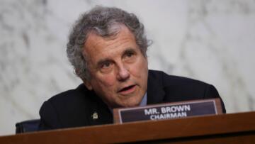 Photograph of Senator Sherrod Brown at a podium with a nameplate that says "MR. BROWN CHAIRMAN"