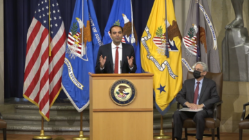 Rohit Chopra stands at a podium in the Department of Justice auditorium.