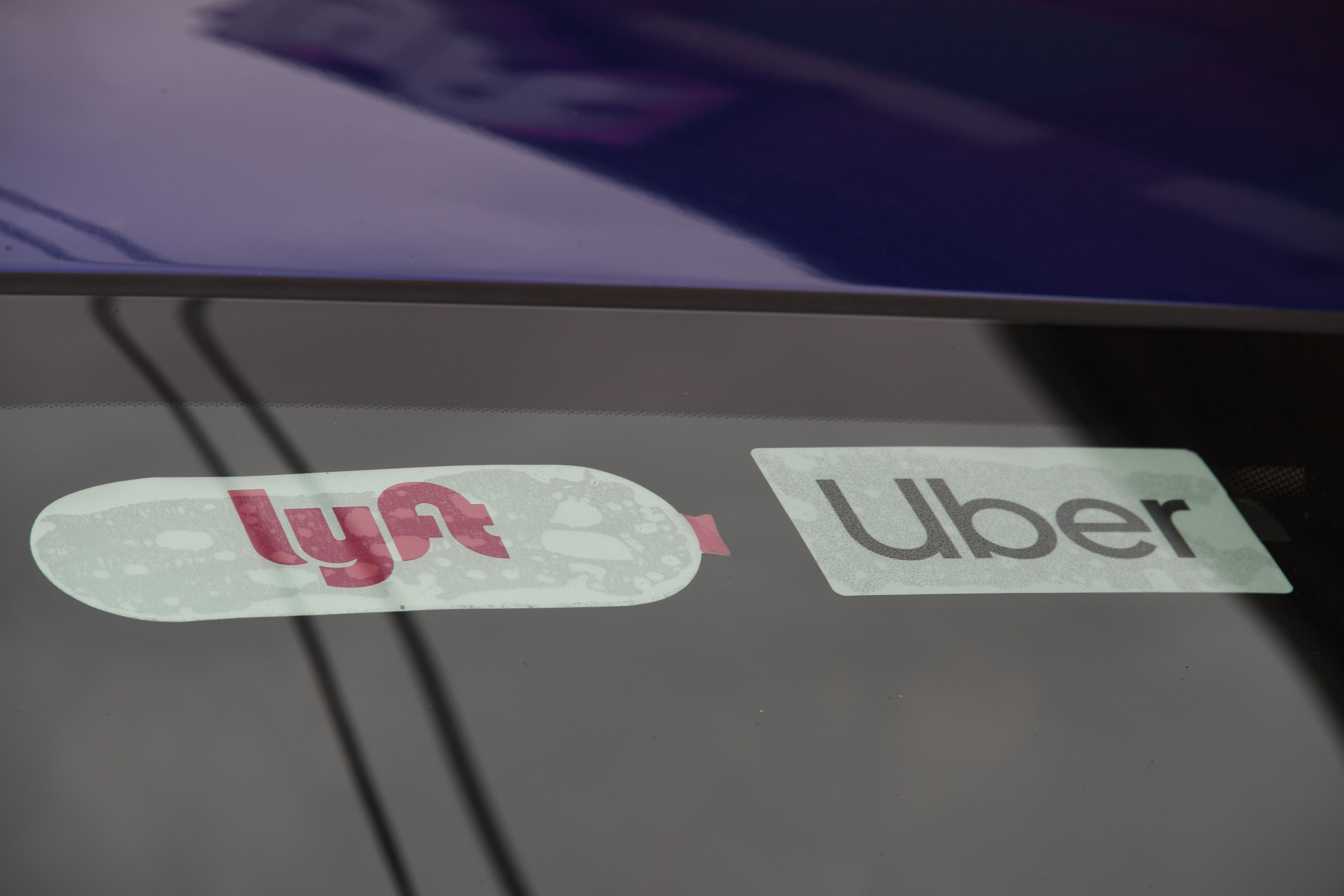 Image of car windshield with one Lyft and one Uber sticker