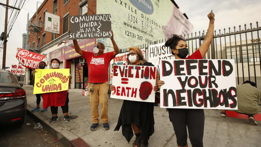 Housing advocates and tenants gathered against eviction of tenants in downtown Los Angeles, holding protest signs written in English and Spanish.