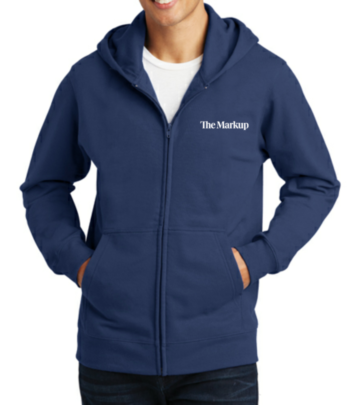 Photo of a model wearing a dark blue sweatshirt with a small white The Markup logo on one side