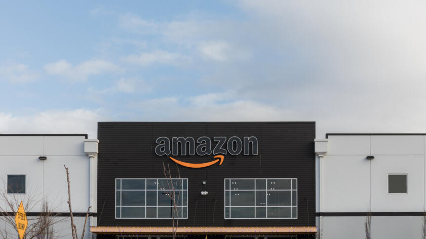 Photo of the front of an Amazon warehouse, with the logo in the center.