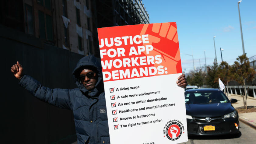 Photo of a man holding a sign that says Justice for App Workers Demands: with a list of demands
