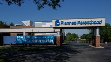 Photograph of a Planned Parenthood building with a sign at the front that says "Now Open by Appointment."