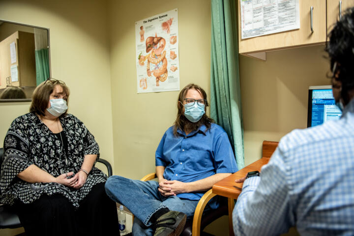 John Lewis sits in a doctor's office with his partner, Ava Williamson.