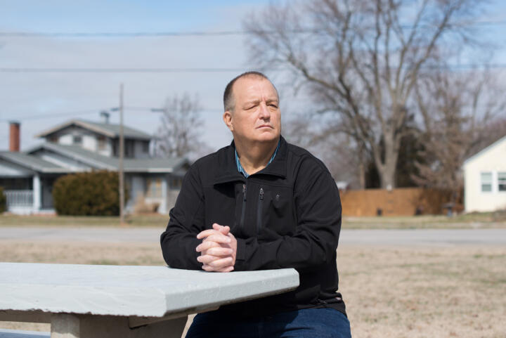 Billy Ruddock sits at a table outside near his home.
