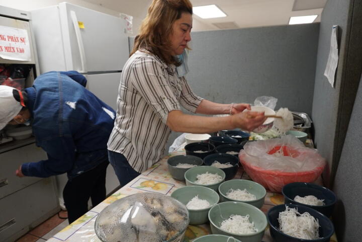 Photograph of Duyen Hoang in a kitchen putting noodles in a bowl.