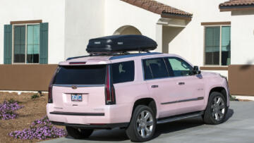 Photograph of a pink Mary Kay Cadillac Escalade parked in the driveway of a home.