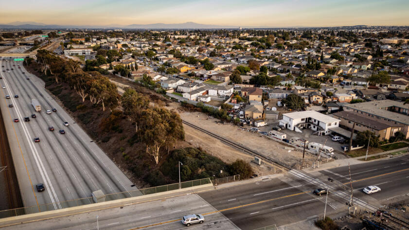 Overhead drone shot of the 105 freeway at sunset, next to houses in South Los Angeles