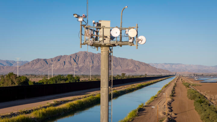 Photograph of a surveillance tower monitor, with a background landscape of a river and mountains