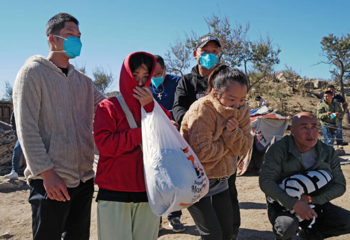 Photo of Chinese migrants, bundled up and huddling for warmth at the U.S.-Mexico border