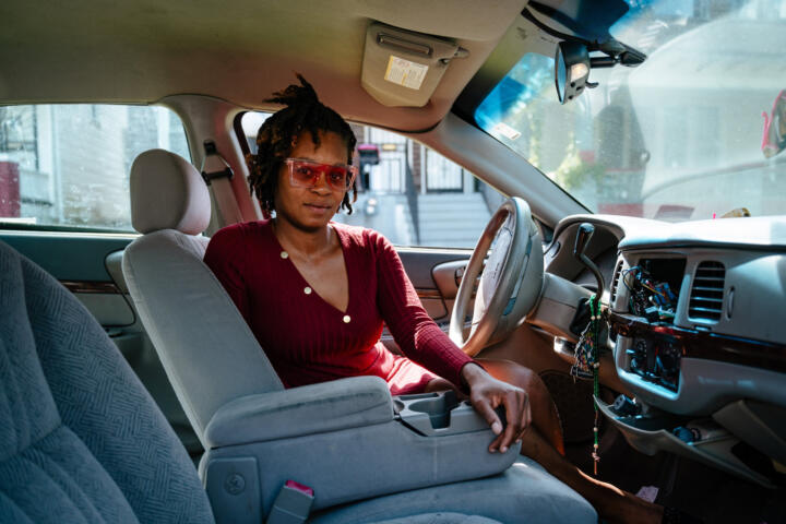 Photo of Melissa Love taken from inside her car, who’s in the driver’s seat looking toward the camera in the passenger seat