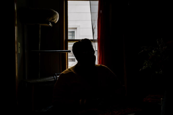 Photo of the silhouette of Alana sitting in her home, backlit by a window behind her