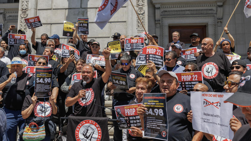 Ride-share driver and SEIU Gig Workers Union member John Mejia, center, speaks during a press conference outside of the Supreme Court of California in San Francisco on May 21, 2024. The state Supreme Court heard oral arguments on Prop. 22, a ballot initiative that allows ride-share companies, such as Uber and Lyft, to classify drivers as independent contractors.