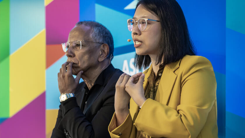 Sisi Wei, right, and Dean Baquet in front of a colorful background at the Aspen Ideas Festival in June