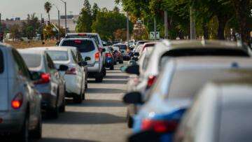 A view from behind of two rows of cars sitting idle during a traffic jam on a road.