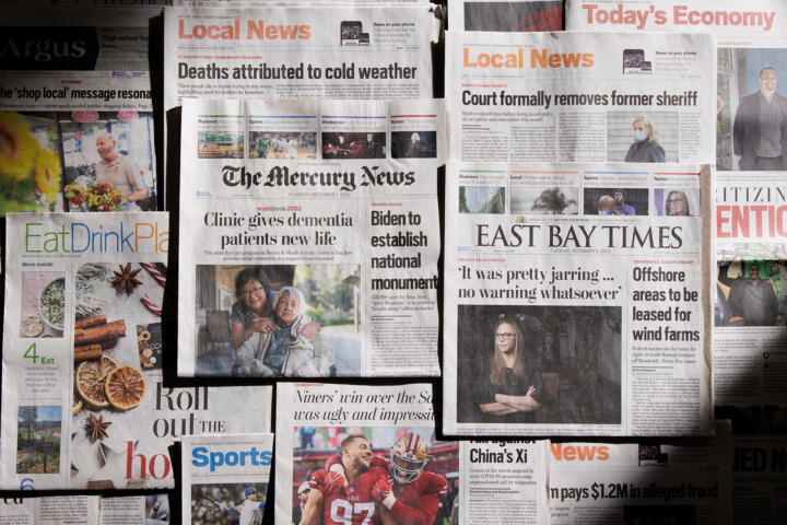 Various front pages of local print newspapers lay on the floor.